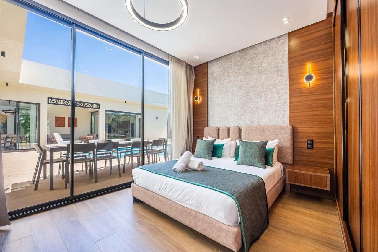 Chambre 2 : lit double et grande baie vitrée ouverte sur la terrasse et la piscine