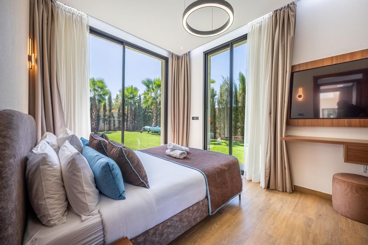 Chambre 4 : lit double et deux baies vitrées ouvertes sur le jardin et les palmiers