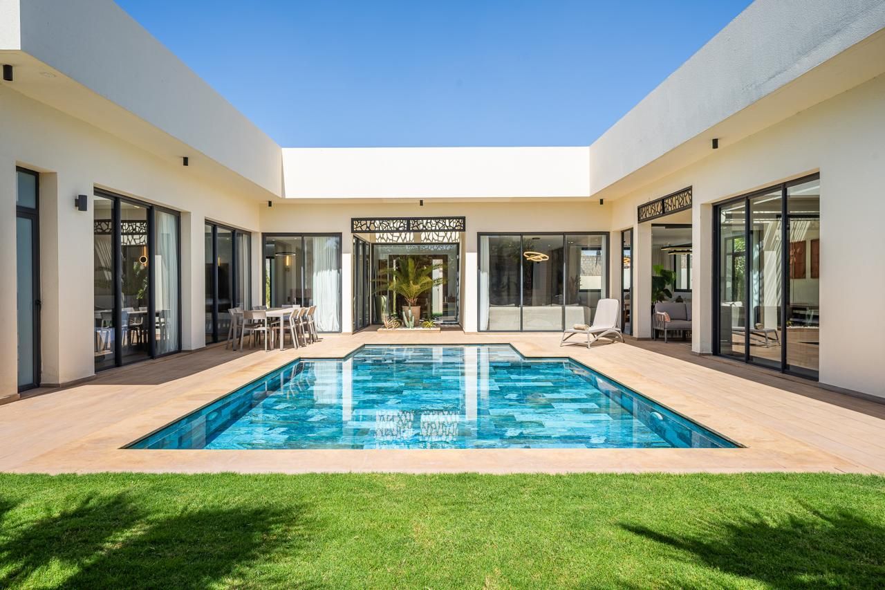 La piscine de jour, au cœur du patio entouré des chambres et des salons vitrés